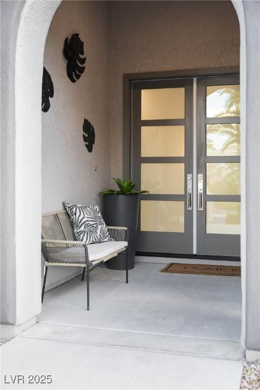 view of exterior entry with stucco siding and french doors