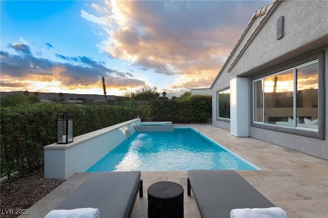 pool at dusk with fence, a fenced in pool, and a patio area