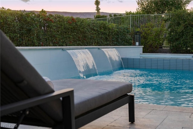 pool at dusk featuring a fenced in pool