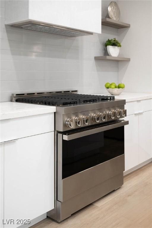 kitchen with stainless steel range with gas stovetop, white cabinets, modern cabinets, and light countertops
