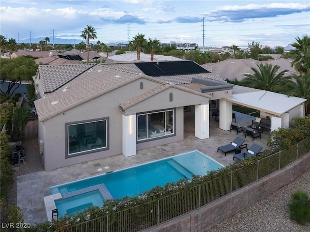 back of property with a fenced backyard, stucco siding, a patio area, a pool with connected hot tub, and a tile roof