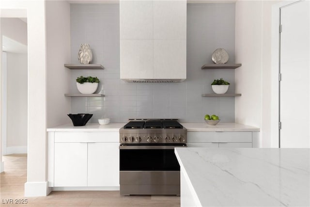 kitchen with stainless steel range with gas cooktop, open shelves, white cabinets, and tasteful backsplash