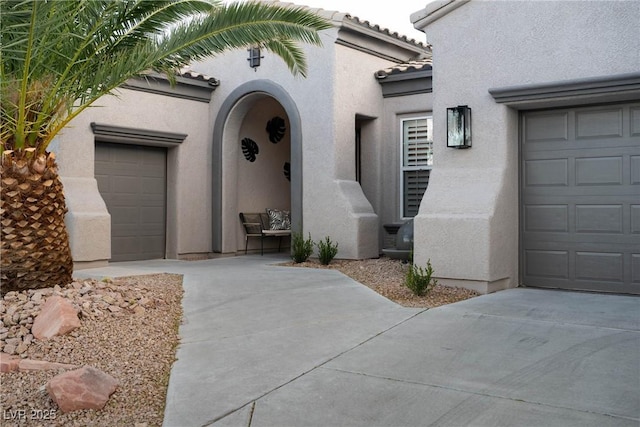 doorway to property with stucco siding, concrete driveway, and a tile roof