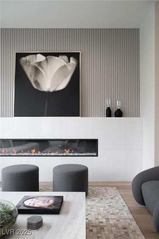interior space with a glass covered fireplace, wallpapered walls, and wood finished floors