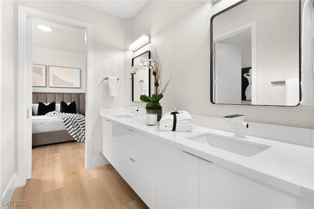full bathroom with double vanity, a sink, connected bathroom, and wood finished floors