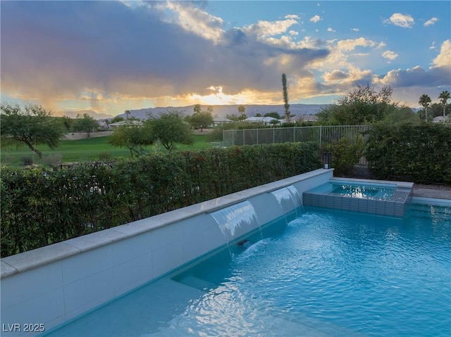 view of swimming pool featuring a fenced backyard and a pool with connected hot tub