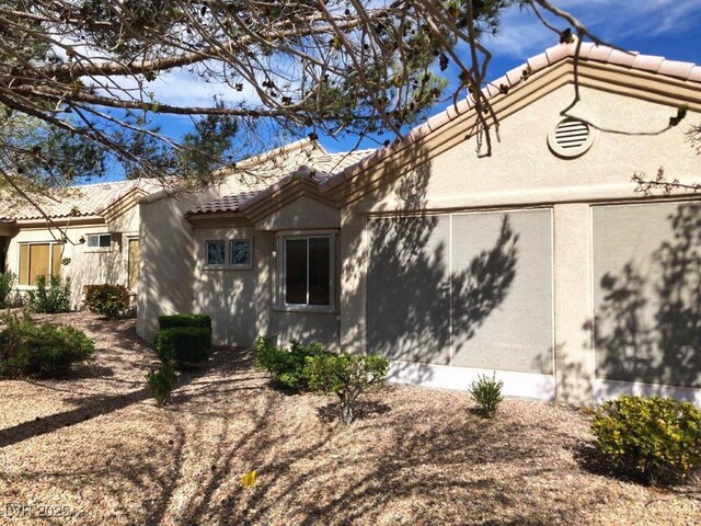 exterior space featuring a tile roof and stucco siding