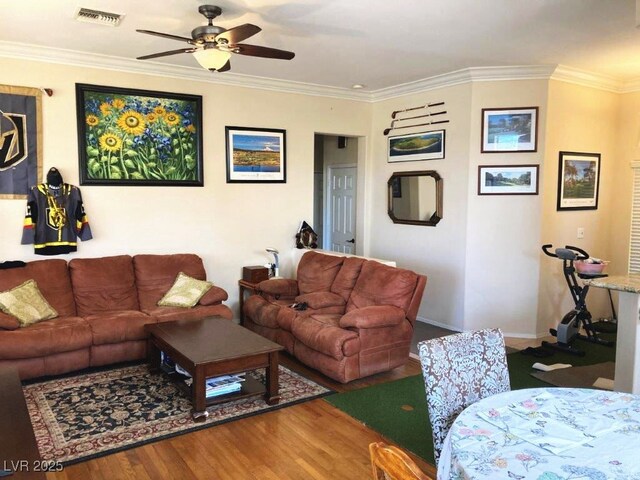 living area with wood finished floors, visible vents, crown molding, and ceiling fan