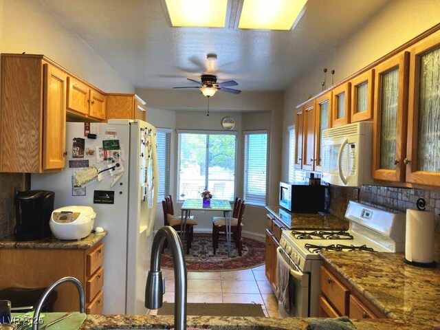 kitchen featuring light tile patterned flooring, glass insert cabinets, a ceiling fan, white appliances, and brown cabinets