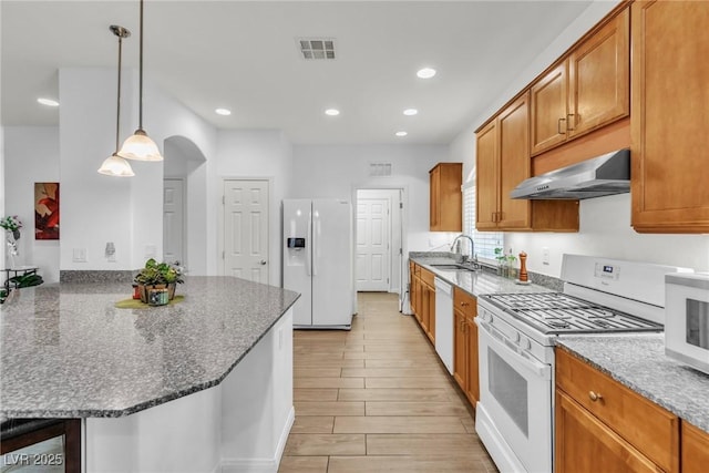 kitchen featuring white appliances, a sink, extractor fan, a peninsula, and dark stone countertops