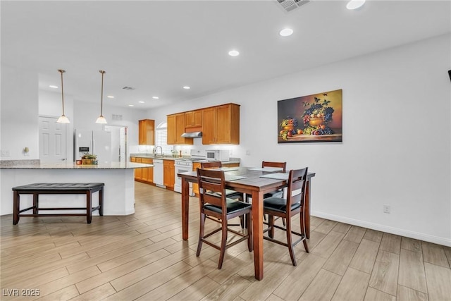 dining space with light wood finished floors, recessed lighting, and baseboards