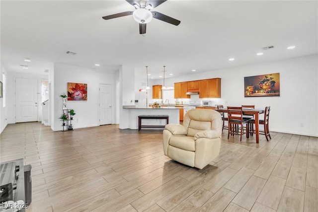 living area featuring a ceiling fan, recessed lighting, light wood-style flooring, and baseboards