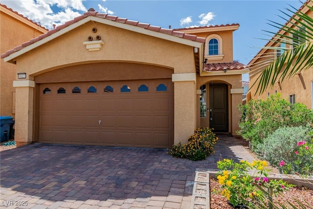 view of front of property with a tiled roof, stucco siding, an attached garage, and decorative driveway