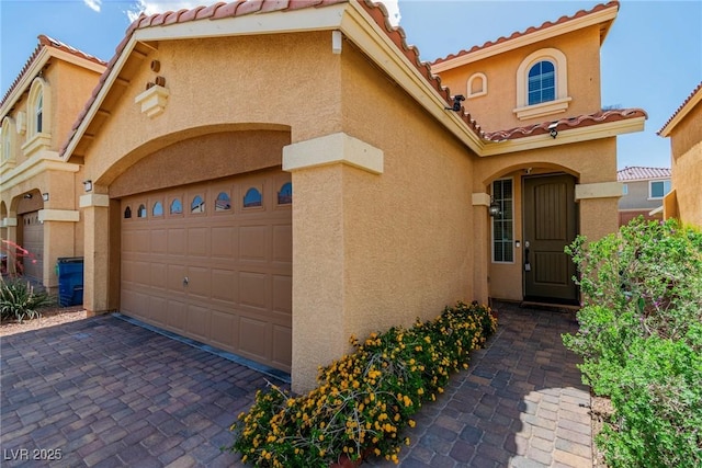 mediterranean / spanish house featuring a tile roof, stucco siding, and decorative driveway