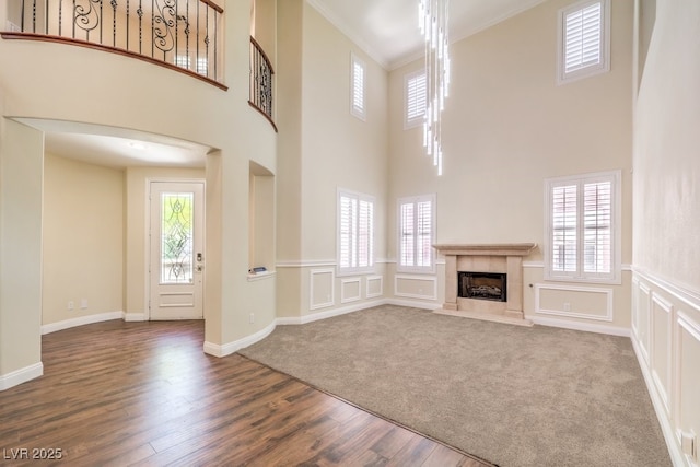 8429 Brackenfield Ave, Las Vegas, NV 89178 - unfurnished living room featuring dark wood-style floors, a fireplace, crown molding, a towering ceiling, and a decorative wall
