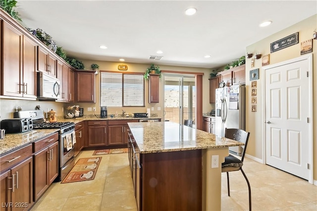 2612 Tullamore Creek Ln, Laughlin, NV 89029 - kitchen featuring appliances with stainless steel finishes, a center island, a sink, a kitchen bar, and light tile patterned floors