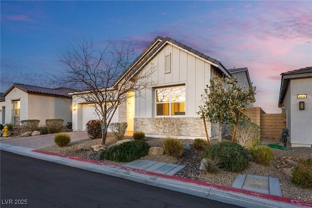 8944 Skye Canyon Ranch St, Las Vegas, NV 89166 - view of front facade with a garage, board and batten siding, driveway, a tiled roof, and fence