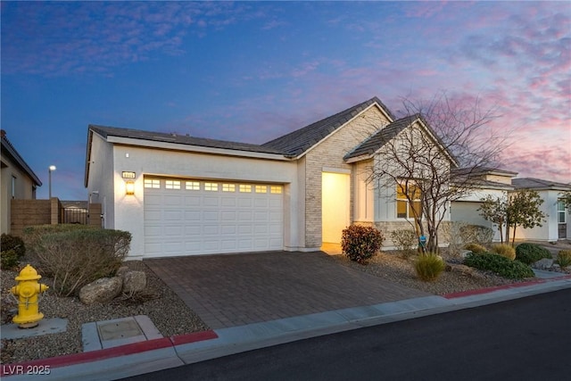 8944 Skye Canyon Ranch St, Las Vegas, NV 89166 - view of front facade featuring decorative driveway, an attached garage, stucco siding, and stone siding