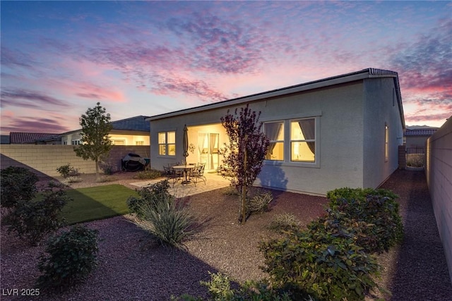 8944 Skye Canyon Ranch St, Las Vegas, NV 89166 - back of house at dusk with a fenced backyard, stucco siding, and a patio