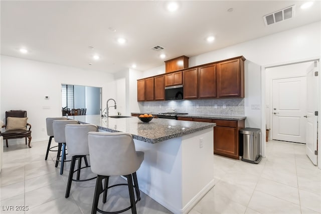 10216 Chrysolite Pl, Las Vegas, NV 89143 - kitchen featuring a sink, decorative backsplash, a center island with sink, light tile patterned floors, and a kitchen breakfast bar