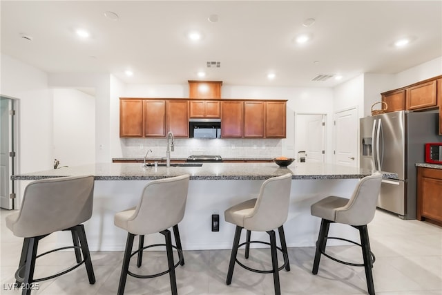 10216 Chrysolite Pl, Las Vegas, NV 89143 - kitchen featuring a sink, stainless steel fridge with ice dispenser, decorative backsplash, an island with sink, and a kitchen bar