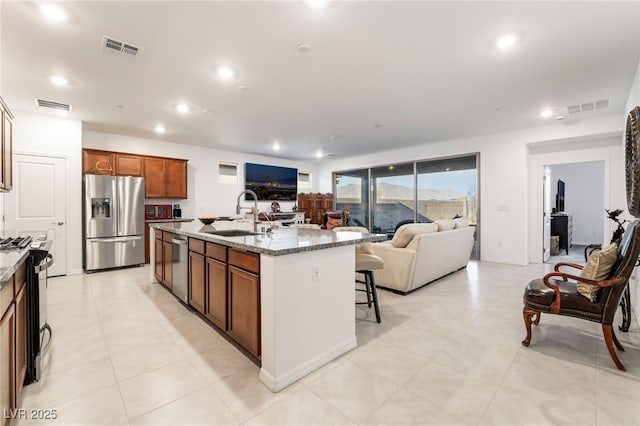 10216 Chrysolite Pl, Las Vegas, NV 89143 - kitchen featuring appliances with stainless steel finishes, open floor plan, a sink, light stone countertops, and recessed lighting