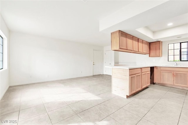 kitchen featuring light countertops, a sink, a raised ceiling, open floor plan, and light tile patterned floors