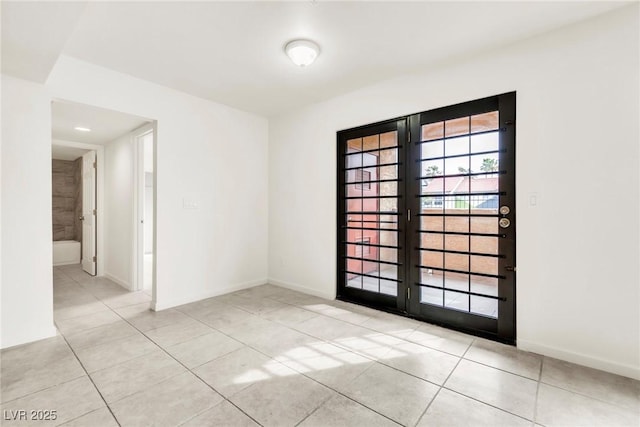 spare room featuring baseboards and light tile patterned floors