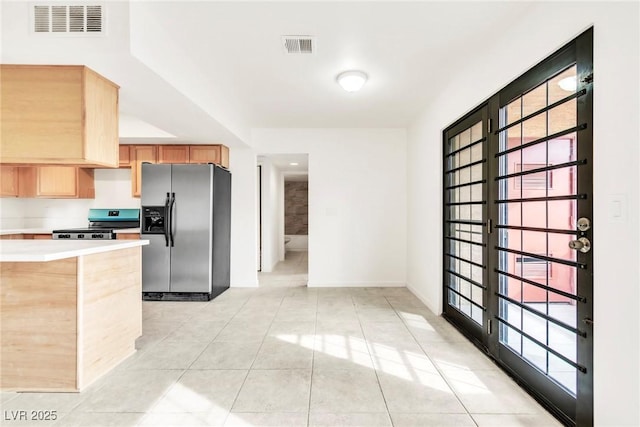 kitchen featuring light countertops, light tile patterned floors, stainless steel appliances, light brown cabinets, and visible vents