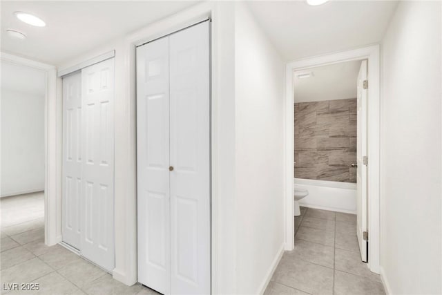 hallway featuring baseboards and light tile patterned floors