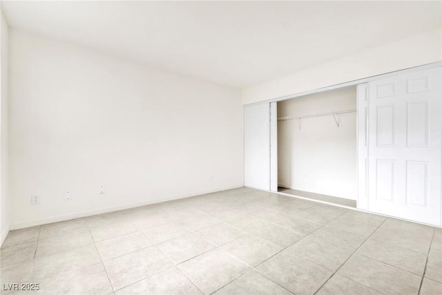 unfurnished bedroom featuring baseboards, a closet, and light tile patterned floors