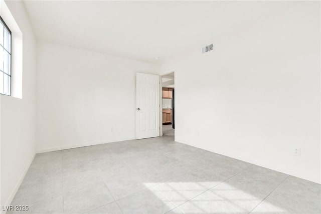 spare room featuring light tile patterned flooring and visible vents