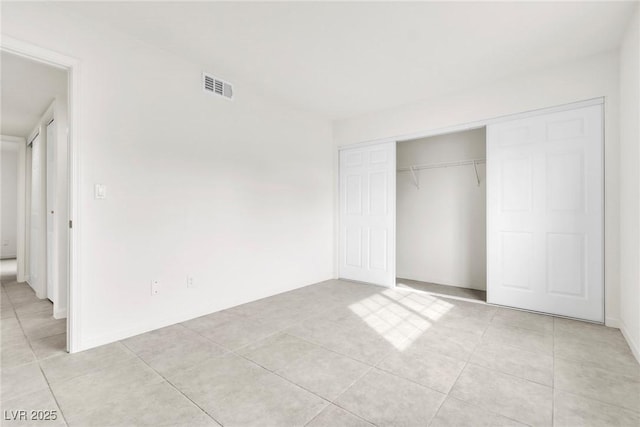unfurnished bedroom with visible vents, a closet, and light tile patterned floors