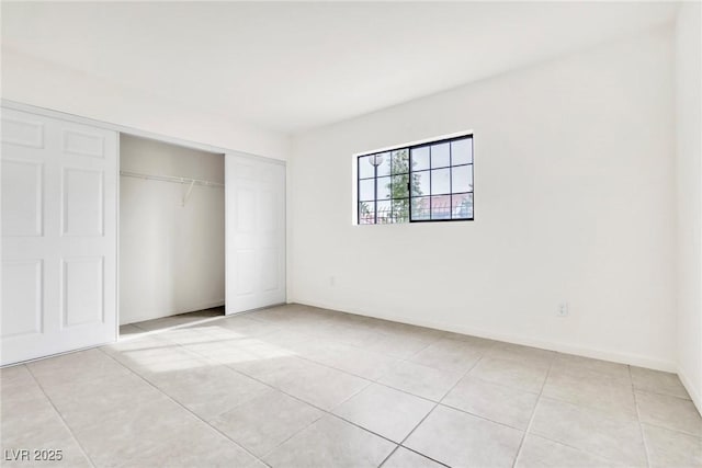 unfurnished bedroom featuring baseboards, a closet, and light tile patterned floors