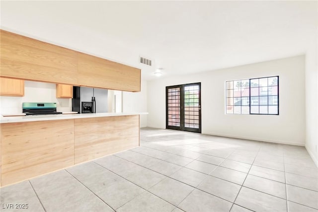 kitchen featuring light countertops, stainless steel range with electric stovetop, light brown cabinetry, light tile patterned flooring, and visible vents
