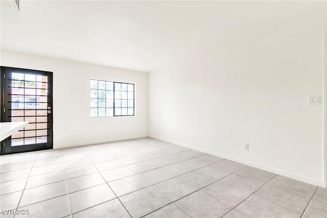 empty room with baseboards and light tile patterned floors