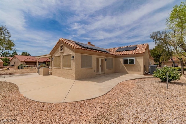 back of property with a tile roof, stucco siding, a patio, and french doors