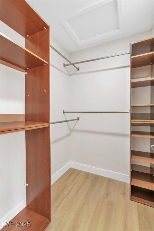 spacious closet with light wood finished floors and attic access