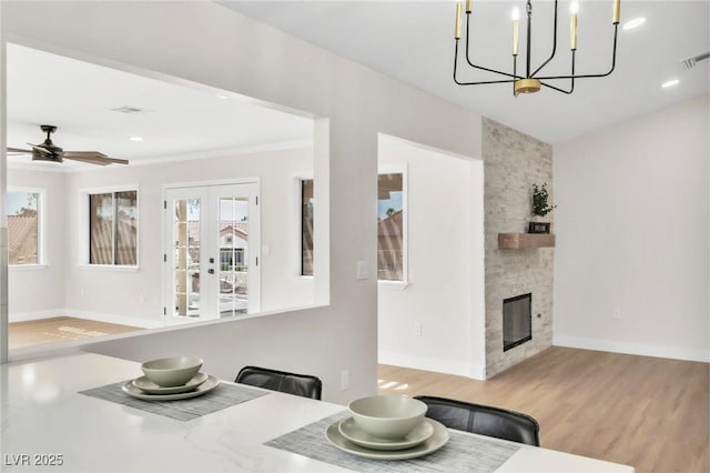 kitchen with baseboards, wood finished floors, recessed lighting, a stone fireplace, and ceiling fan with notable chandelier