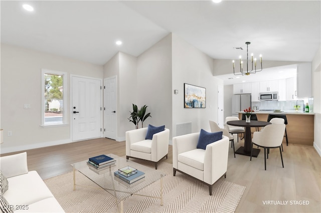 living area with baseboards, visible vents, a notable chandelier, and light wood finished floors