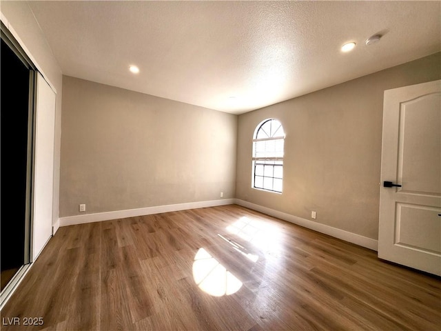 4050 Pacific Harbors Dr Unit 209, Las Vegas, NV 89121 - unfurnished bedroom with baseboards, a textured ceiling, wood finished floors, and a closet