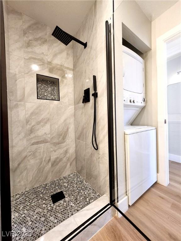 4050 Pacific Harbors Dr Unit 209, Las Vegas, NV 89121 - bathroom with baseboards, a stall shower, stacked washing maching and dryer, and wood finished floors
