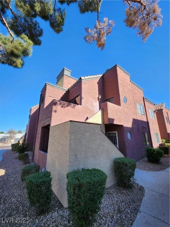 4050 Pacific Harbors Dr Unit 209, Las Vegas, NV 89121 - view of side of home with stucco siding and a chimney