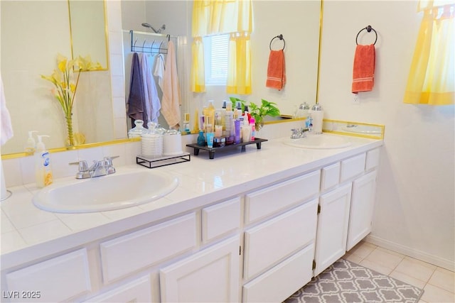 bathroom with double vanity, a sink, baseboards, and walk in shower