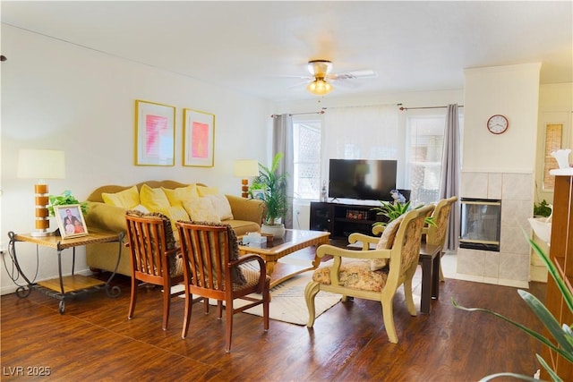 living area featuring a fireplace, a ceiling fan, and wood finished floors