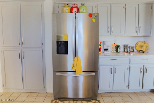 kitchen with light tile patterned floors, light countertops, white cabinetry, and stainless steel refrigerator with ice dispenser