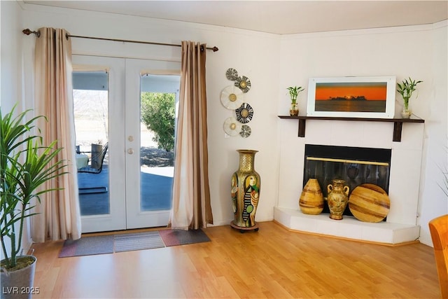 entryway with french doors, wood finished floors, and a fireplace