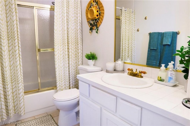 bathroom with toilet, tile patterned floors, vanity, and bath / shower combo with glass door