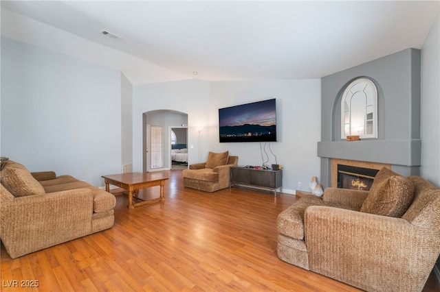 1010 Armillaria St, Henderson, NV 89011 - living area featuring visible vents, arched walkways, light wood-type flooring, and a glass covered fireplace