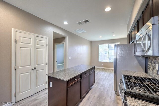4516 Townwall St, Las Vegas, NV 89115 - kitchen with light wood finished floors, stainless steel microwave, visible vents, range with gas cooktop, and dark brown cabinets